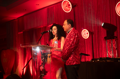 Man and woman in red speaking at podium.